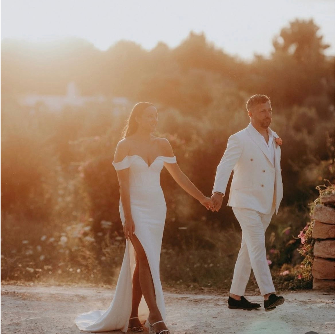 Bride and groom at sunset, groom in a white double-breasted suit