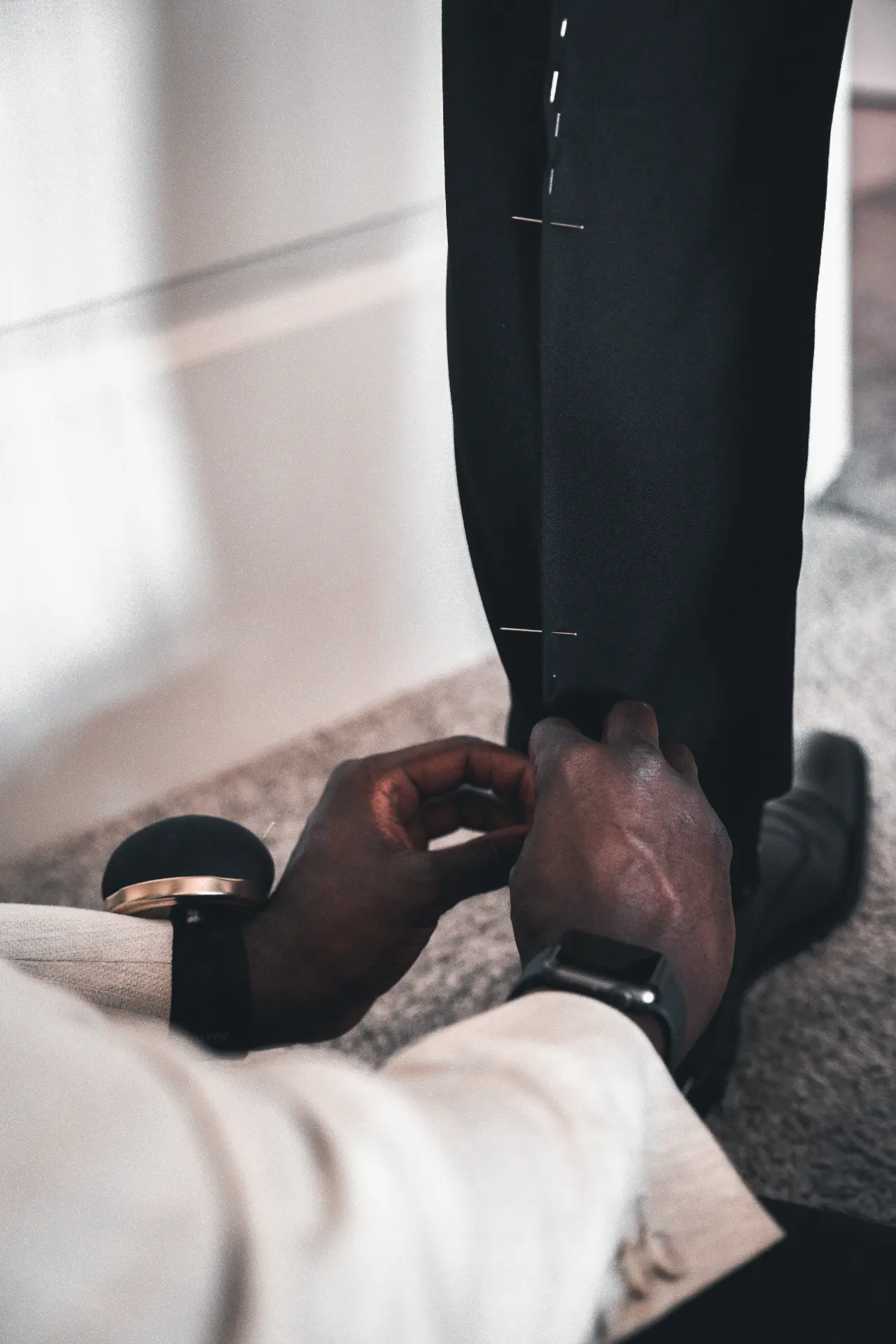 Tailor pinning a trouser hem during a fitting